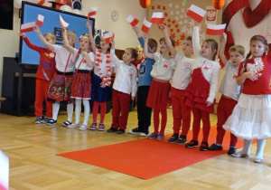 Grupa dzieci z uniesionymi polskimi flagami