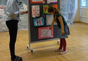 dziecko pokazują swoją pracę konkursową na tablicy