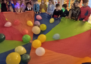 Dzieci trzymające chustę animacyjną z balonami