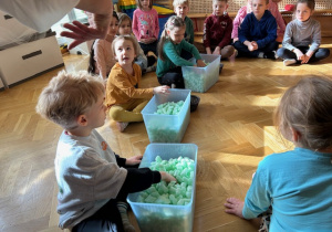 Dzieci szukające w pojemnikach z piankami przedmiotów