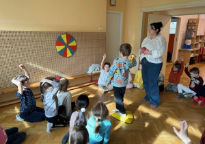 Grupa dzieci i nauczycielka rzucają rzutkami do tarczy