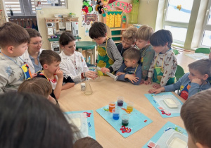 dzieci słuchają studentek - warsztaty chemiczne