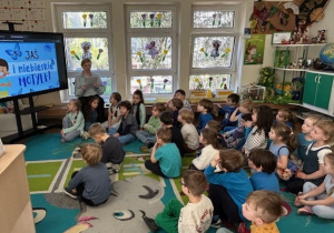 Grupa dzieci oglądająca film edukacyjny na tablicy multimedialnej