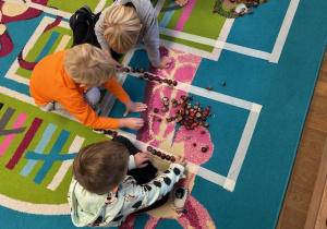 dzieci układają figury z materiału przyrodniczego