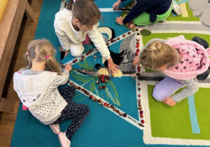 dzieci układają figury z materiału przyrodniczego