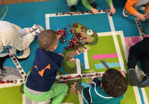 dzieci układają figury z materiału przyrodniczego