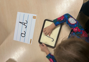 dziewczynka rysuje po kaszy mannej