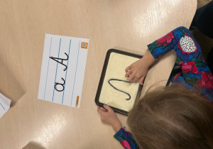 dziewczynka rysuje po kaszy mannej