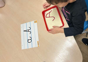 chłopiec rysuje po kaszy mannej