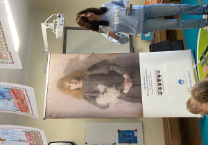 Edukatorka prowadząca spotkanie obok duży format wydruku obrazu "Dziewczynka z chryzantemami"