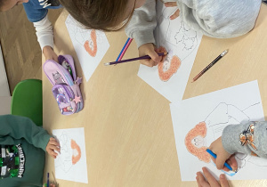 Dzieci przy stole kolorują kolorowankę