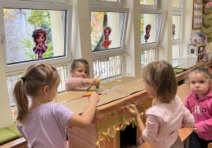 Dzieci ozdabiają budę zrobioną z kartonu