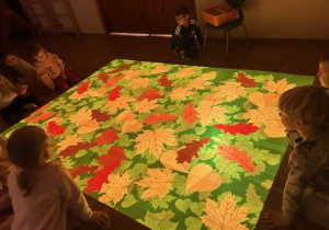 dzieci siedzą i łapią liście na podłodze