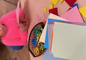 Kolorowe kartki i dziewczynk, która wycina nożyczkami