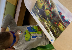 Chłopiec w okularach 3D patrzy na planszę świat dinozaurów