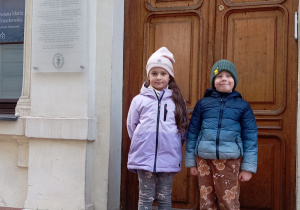 Dwoje dzieci przed drzwiami z dwoma paczkami darów