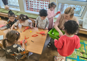 Grupa dzieci młodszych podczas ozdabiania serduszek