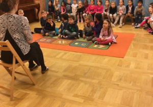dzieci siedzą na dywanie i słuchają pani autorki