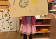dziecko stoi ze swoim rysunkiem